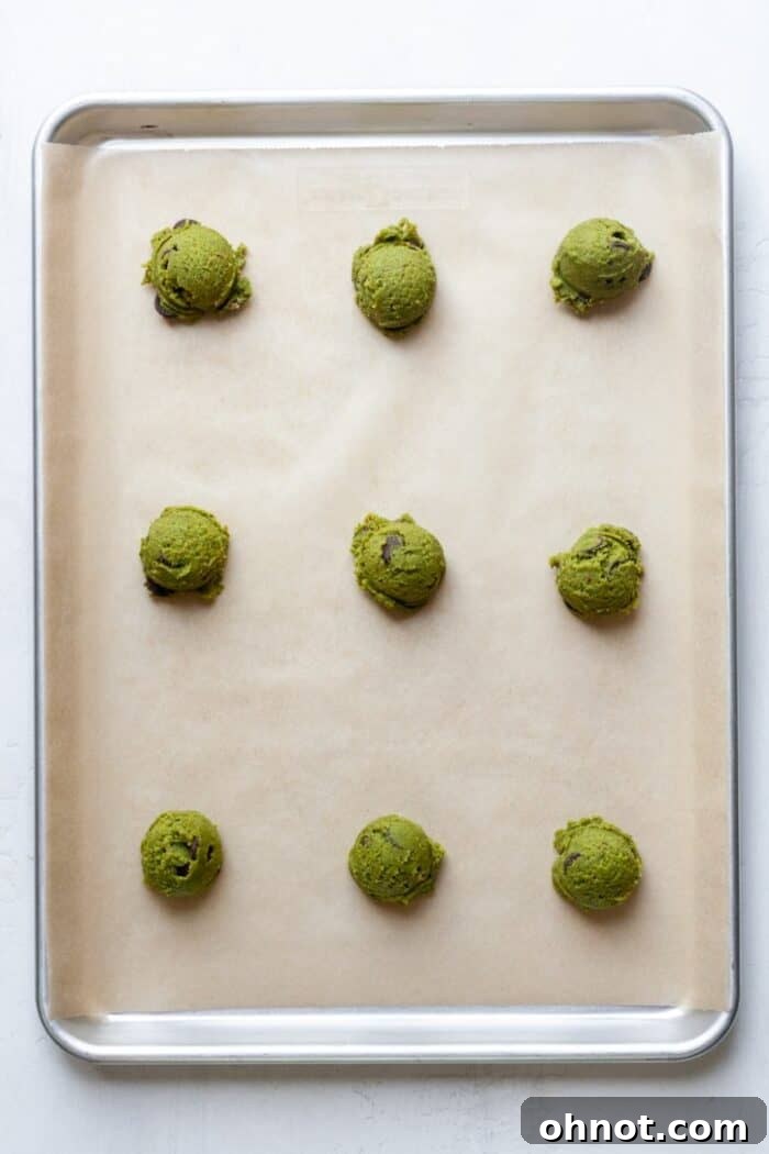 Cookie dough balls neatly arranged on a parchment-lined baking pan