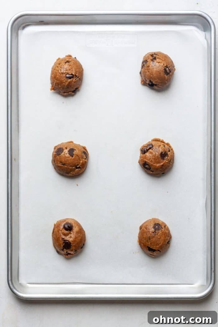 Portioned cookie dough balls ready for baking on a parchment-lined baking sheet.