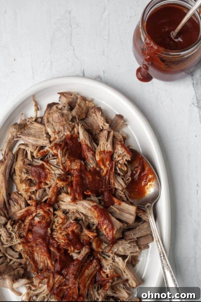 A bowl of Whole30 Slow Cooker Pulled Pork with a fork, ready to be enjoyed
