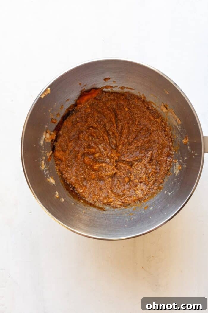 Pumpkin puree and brown sugar being mixed in a bowl, showing the initial wet ingredients.