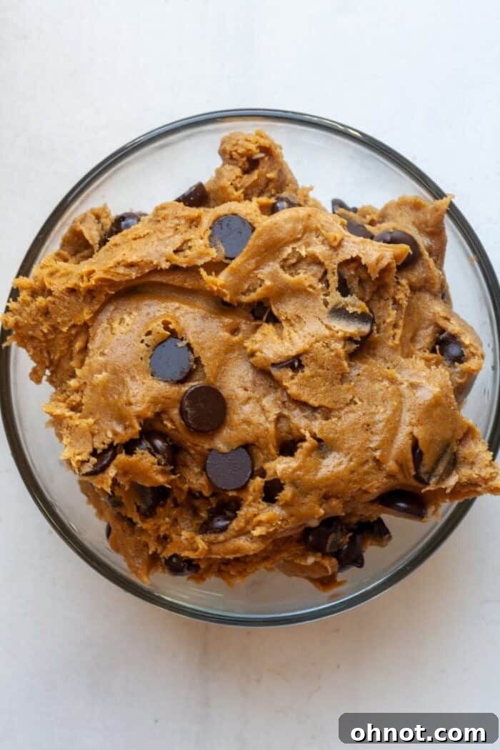 Chocolate chips folded into the pumpkin cookie dough in a bowl, ready for scooping.