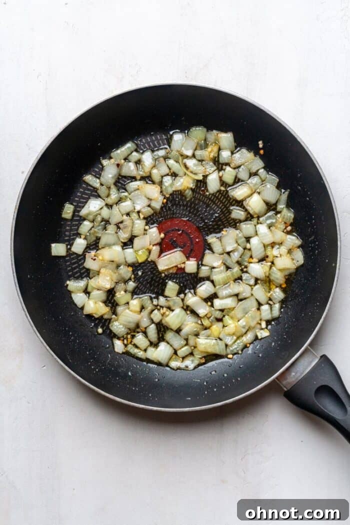 Chopped onions and garlic sautéing in a pan with red pepper flakes