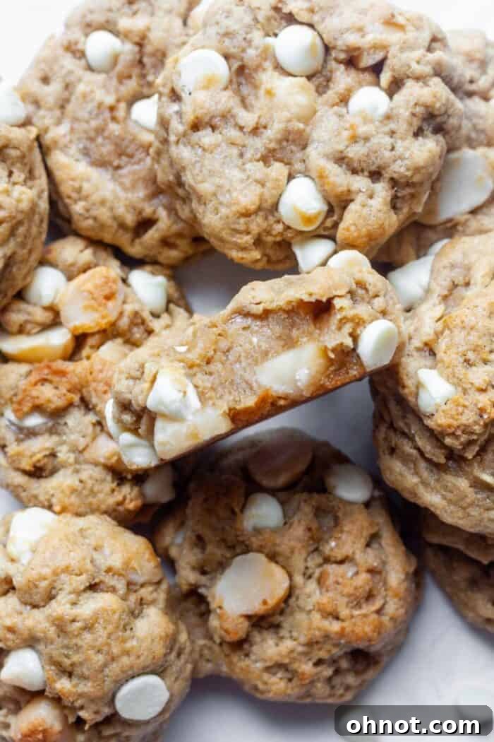 Close-up of a stack of gooey vegan white chocolate macadamia nut cookies, showcasing their irresistible texture.