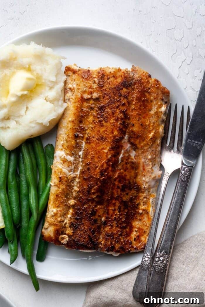 Perfectly cooked blackened mahi mahi on a plate, garnished with fresh herbs and a lemon wedge, showcasing its crispy exterior and flaky texture.