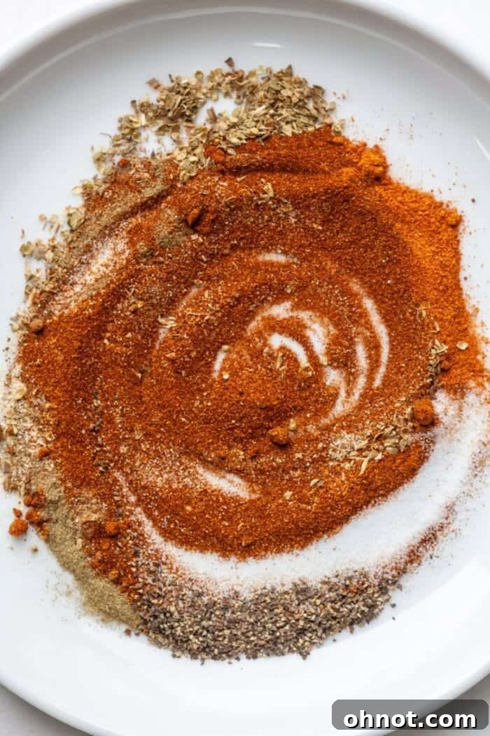 A small bowl filled with a vibrant mix of various spices for Paleo Cajun seasoning, ready to be combined.