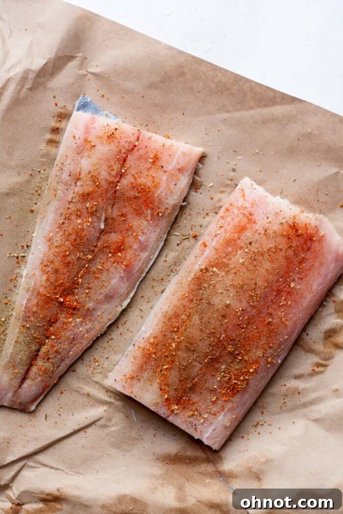 Mahi mahi fillets generously coated with Cajun fish seasoning on a plate, ready for cooking.