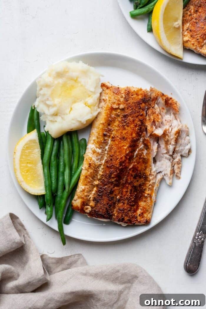 A complete meal featuring blackened mahi mahi alongside roasted potatoes and green beans, garnished with fresh lemon slices.