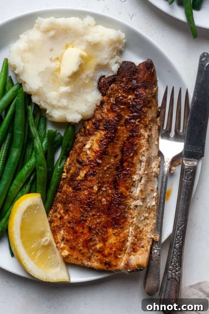 A simple yet elegant presentation of blackened fish on a white plate, highlighting its rich color and inviting texture.