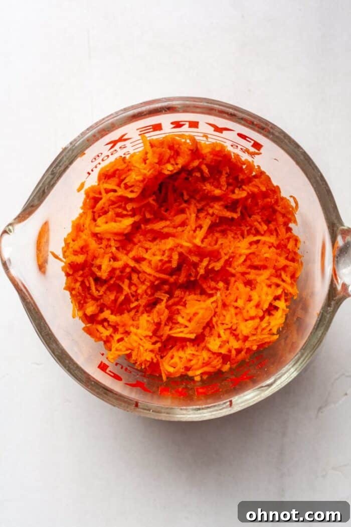 Grated carrots in measuring cup, prepared for baking.