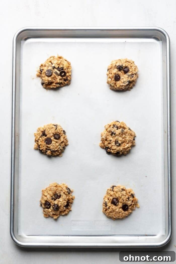 Raw cookie dough balls flattened on a baking sheet