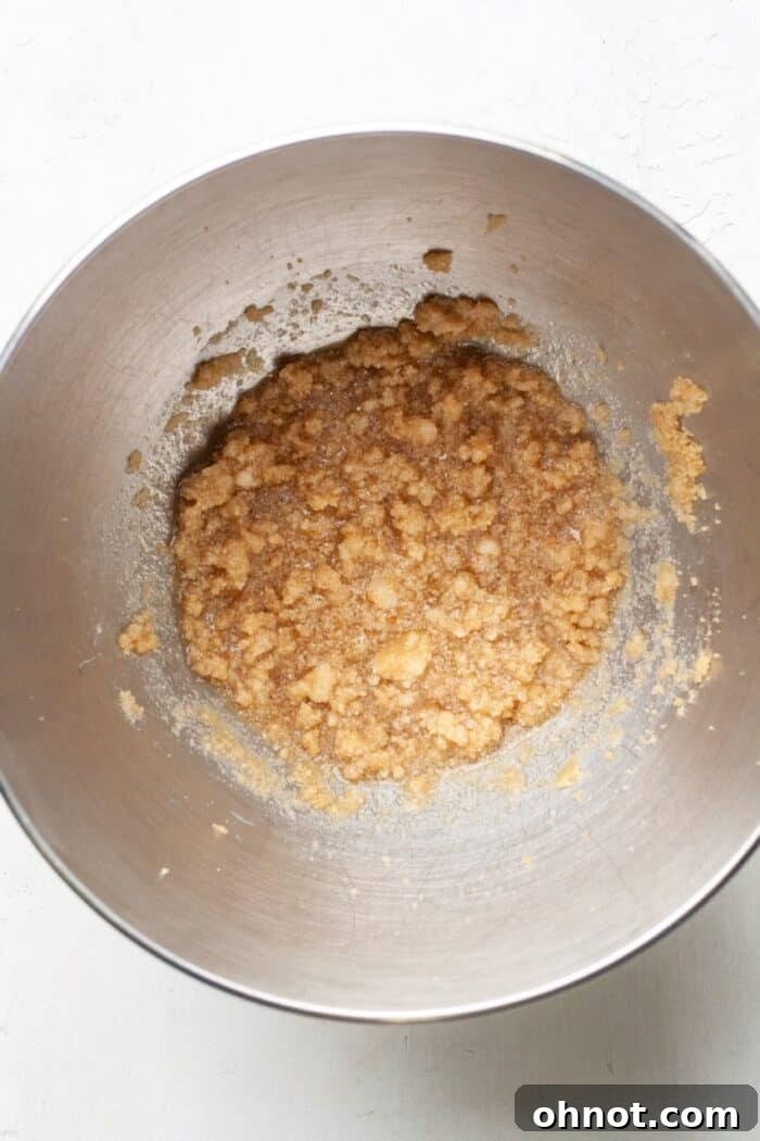 Applesauce and almond milk added to the sugar mixture in a bowl.