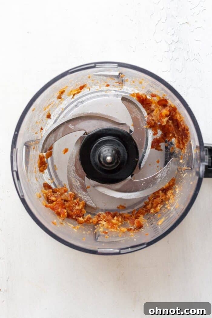 Date paste in food processor, showing the natural sweetener and binder for healthy granola