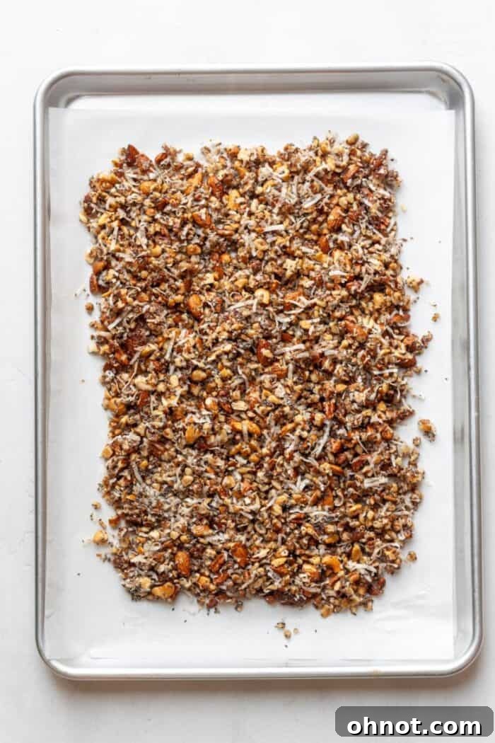 Granola mixture spread evenly on a baking pan, ready for oven baking