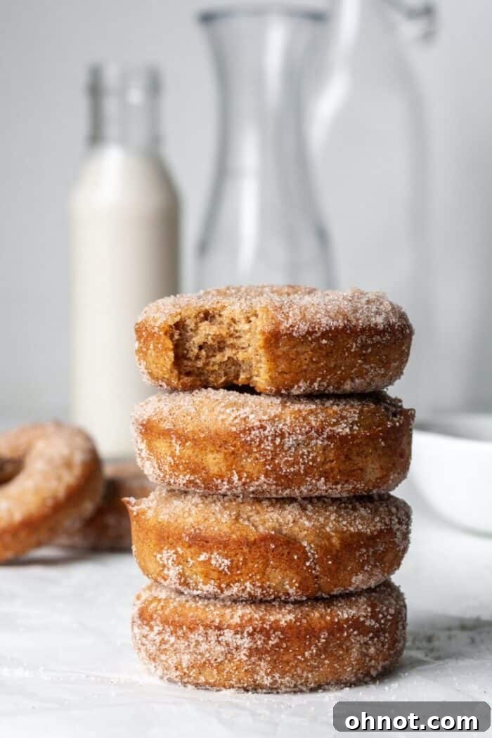 A tall stack of freshly coated gluten-free apple cider donuts on a platter, ready to be served