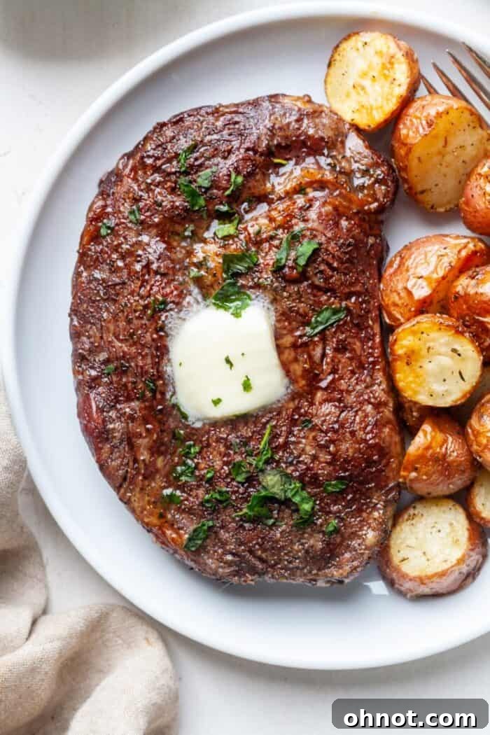 Ribeye steak with roasted potatoes and herbs, showcasing its perfect doneness