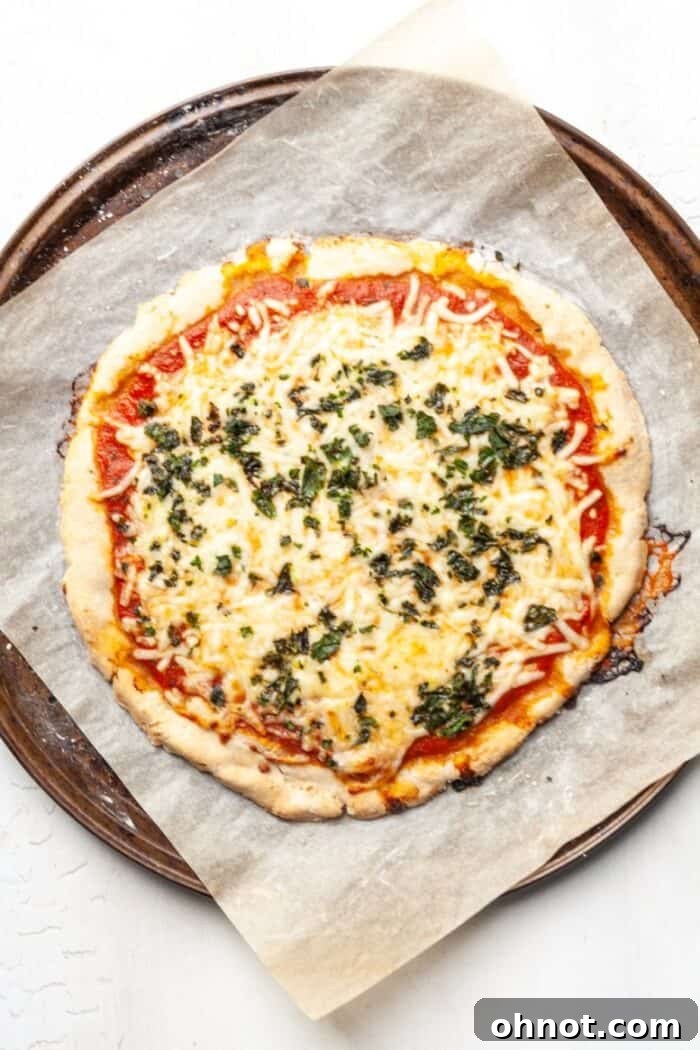 A Paleo pizza on a baking pan, fully topped and ready for its final bake in the oven.
