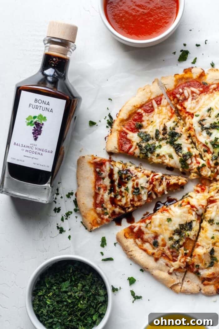 A close-up of a Paleo pizza drizzled with balsamic glaze and garnished with fresh basil.