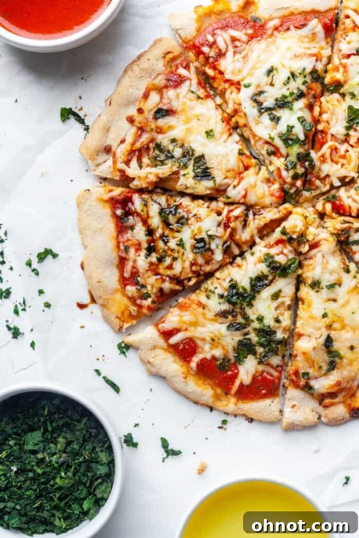 Freshly baked Paleo pizza topped with dairy-free cheese, vibrant green basil leaves, and a drizzle of balsamic glaze.
