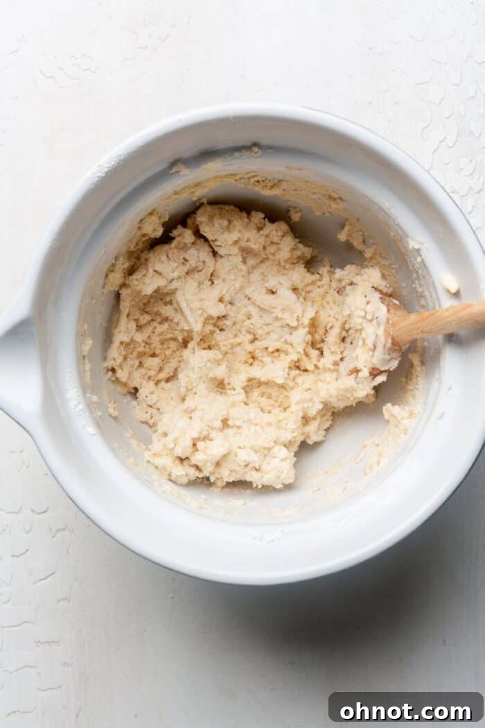 Gluten-free pizza dough forming in a mixing bowl after wet and dry ingredients are combined.