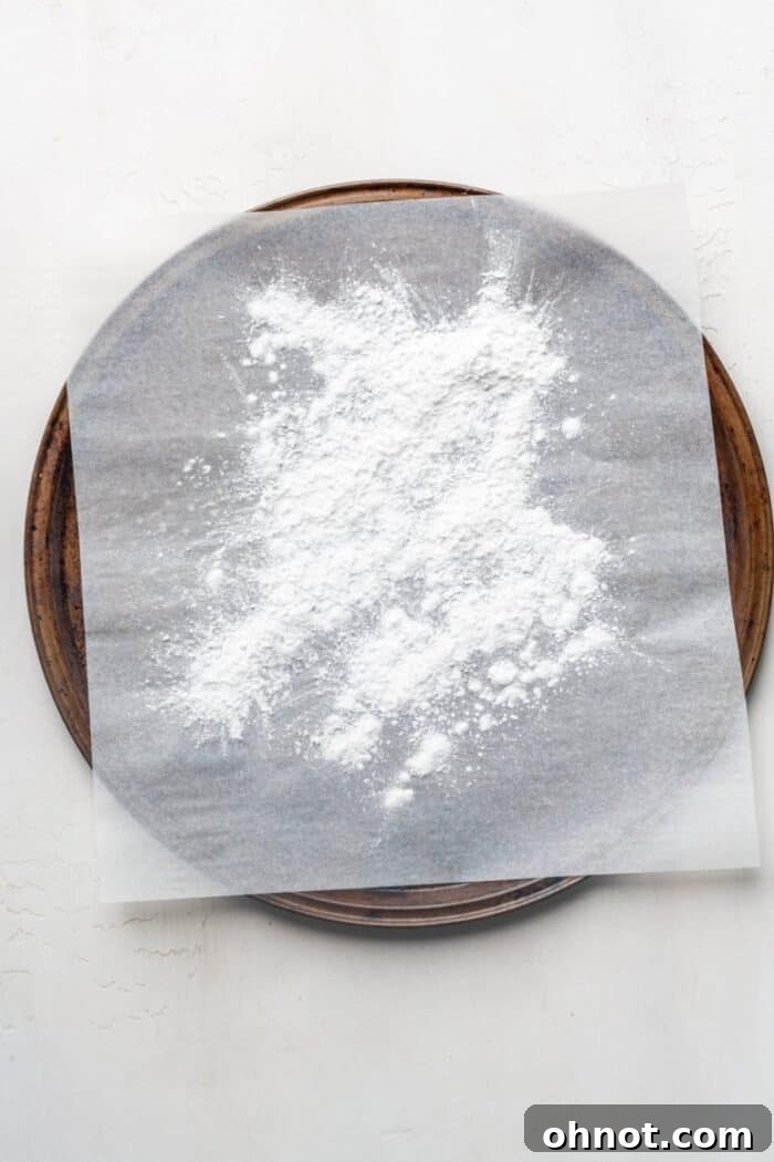 A light dusting of tapioca flour spread across a parchment-lined baking pan, prepared for pizza dough.