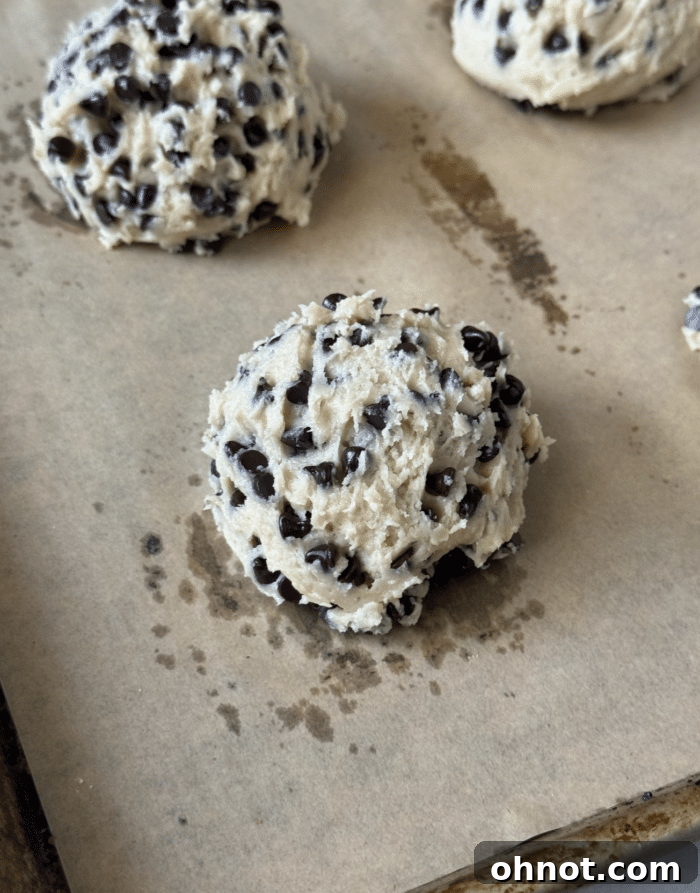Scoops of Greek yogurt cookie dough on a parchment-lined baking sheet.