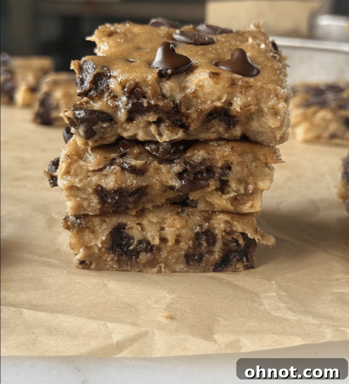 Close-up of freshly baked banana blondies, golden brown with melted chocolate chips visible, served on parchment paper.