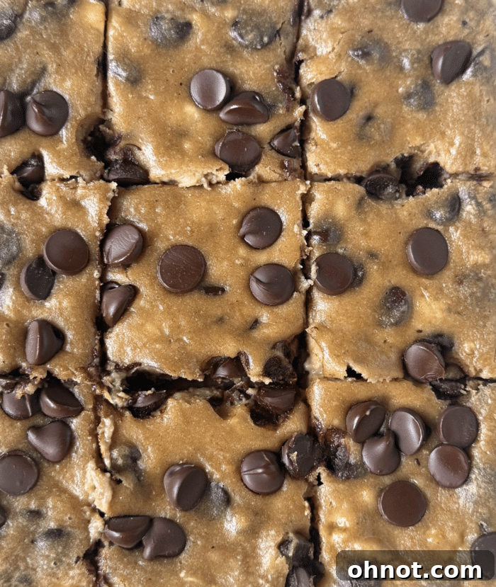 A close-up of square banana blondie bars, golden brown and soft, with visible chocolate chips, arranged neatly.