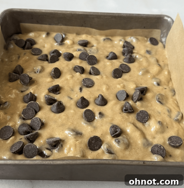A square baking pan filled with unbaked yellow banana blondie batter, ready for the oven.