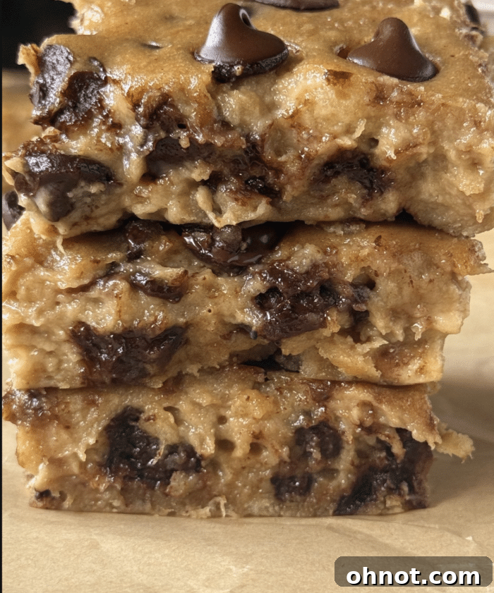 Close-up of a stack of moist banana blondies with melted dark chocolate chips, showing their gooey texture.