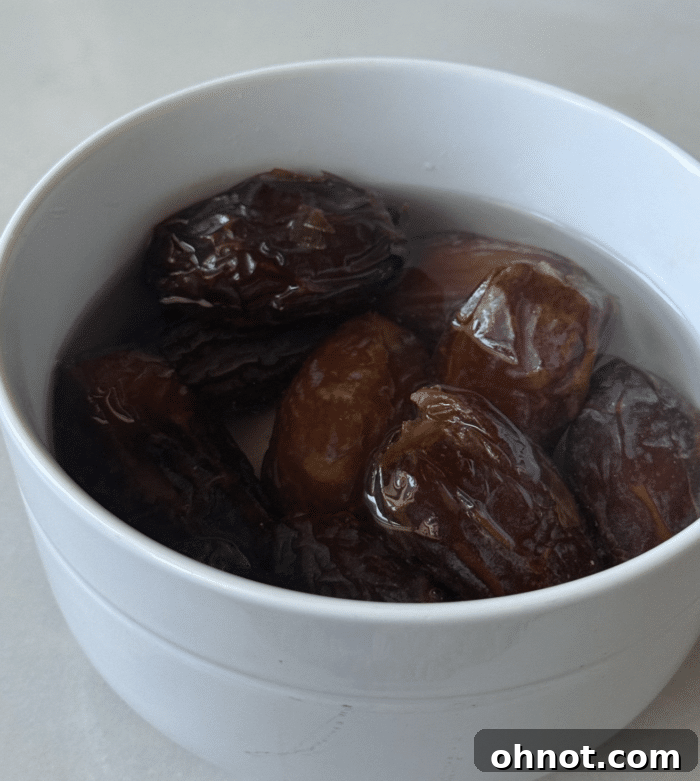 Pitted dates soaking in hot water in a bowl.