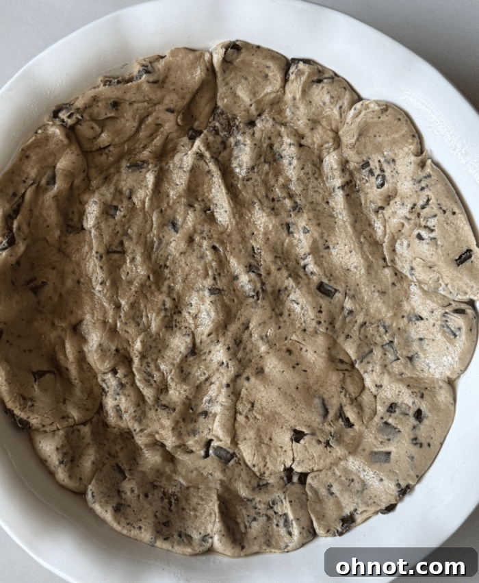 Unbaked cookie dough pressed into a pie plate, forming the base.
