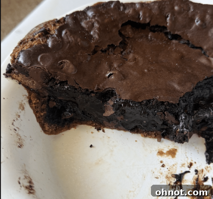 Close-up of a perfectly baked, gooey brownie pie in a round baking pan.