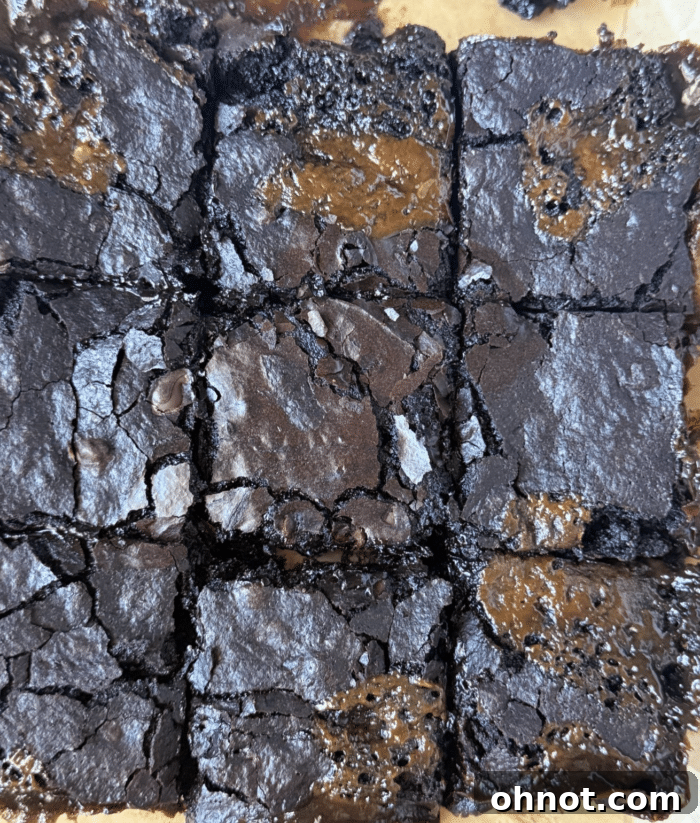 Close-up of freshly sliced caramel brownies, showing a gooey caramel layer between dark chocolate brownie halves.