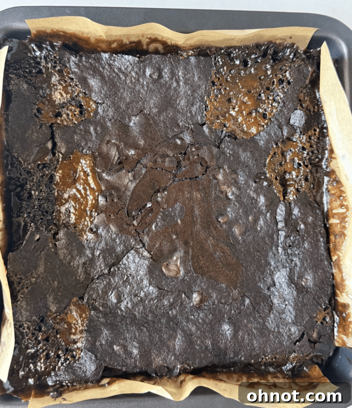 A pan of freshly baked caramel chocolate brownies, golden brown with a slight crackle on top.
