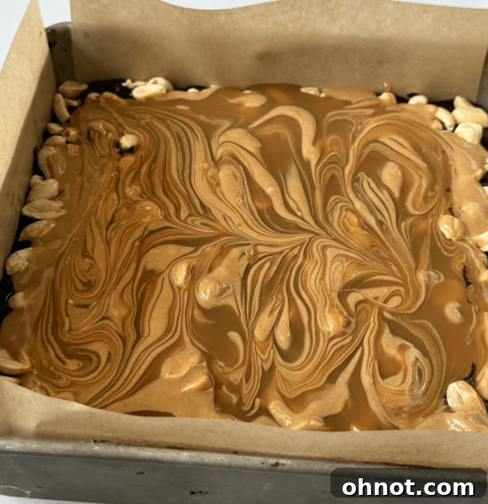 Brownie batter and cookie dough layered in a baking pan, creating the base for Snickers Brookies.