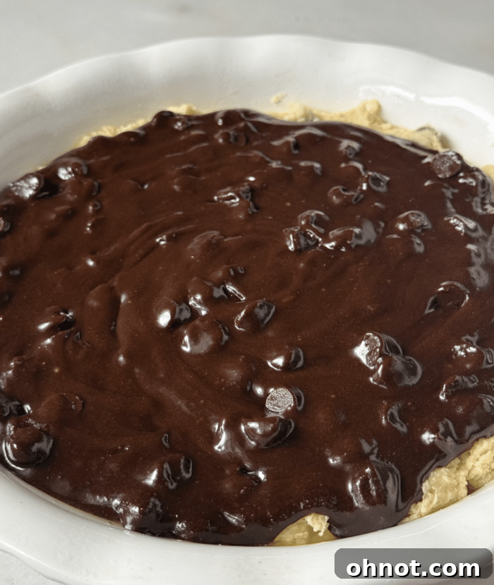Brownie batter poured over the cookie dough layer in the pie pan.
