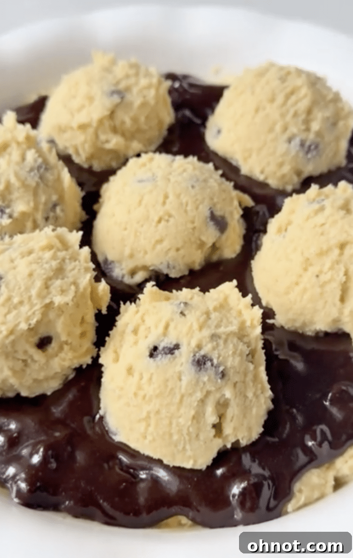 Scoops of remaining cookie dough placed on top of the brownie batter before baking.