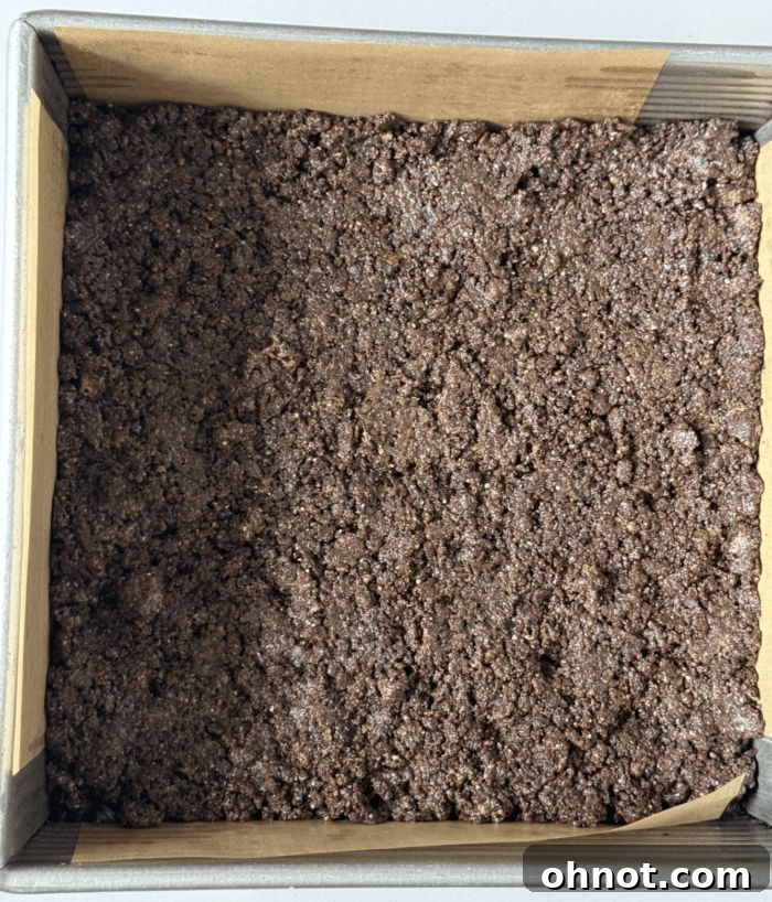 Chocolate cookie crust pressed firmly into a parchment-lined square baking pan.