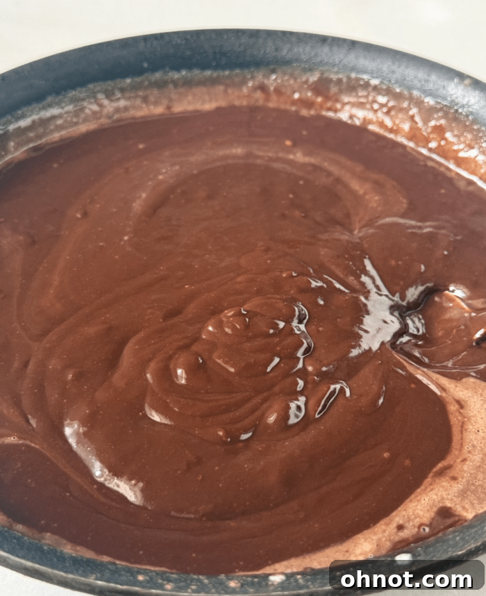 Smooth, glossy chocolate ganache cooling in a pan.