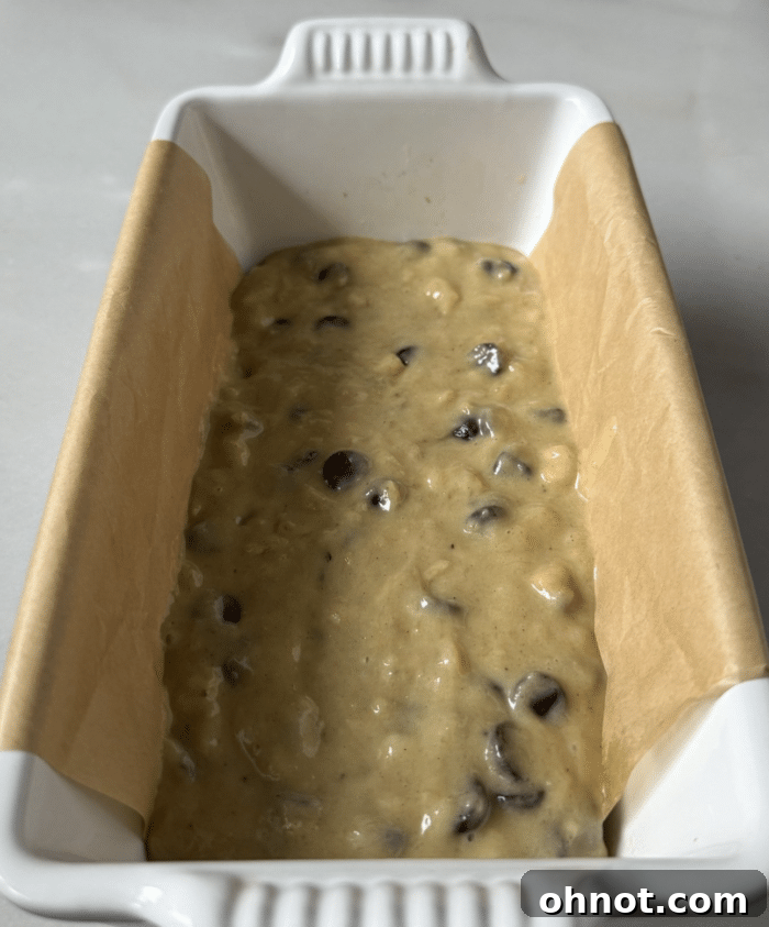 Half of the banana bread batter spread in a loaf pan.