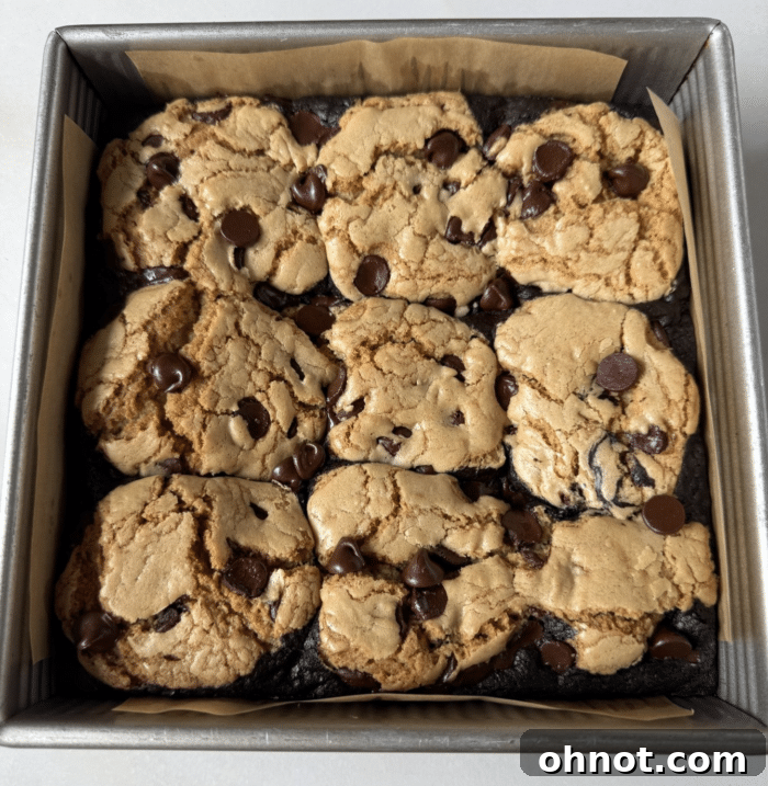 Freshly baked brookie bars cooling in a parchment-lined pan.