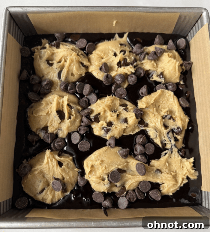 Raw cookie dough balls arranged over brownie batter in a baking pan.